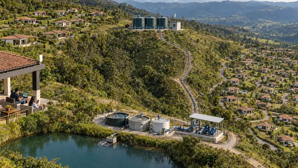 Planta de tratamiento de agua en la montaña: el lago, los tanques de tratamiento y la estación de bombeo, la tubería que sube hasta los tanques de distribución y las casas de la parcelación alrededor